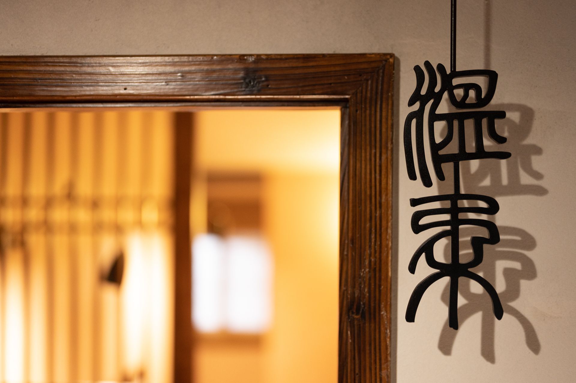 Wooden-framed window with warm light and a black hanging calligraphy decoration on the wall