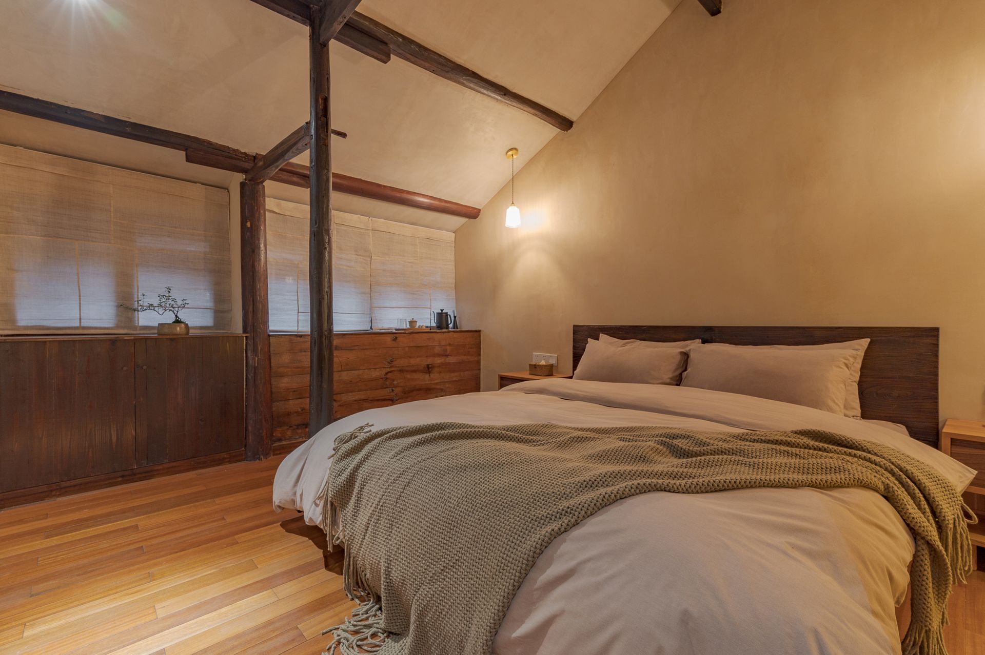 Cozy attic bedroom with a large bed, wood floors, and warm lighting