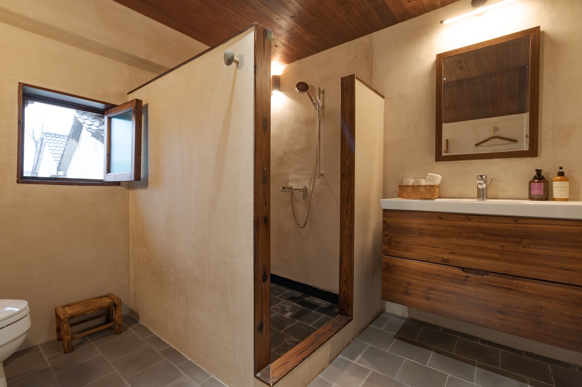 Rustic bathroom with wood vanity, shower stall, tiled floor, and small window
