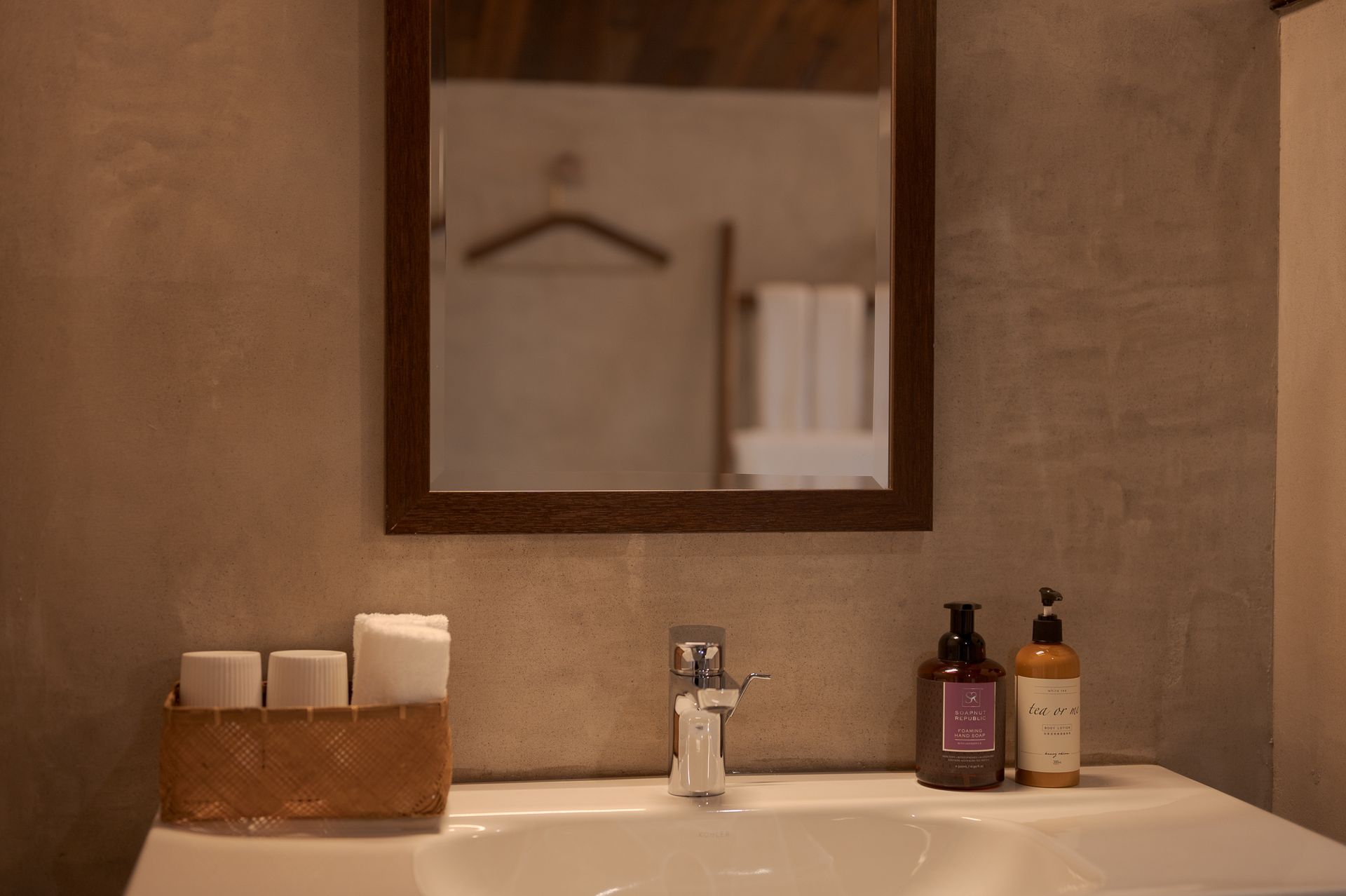 Bathroom sink with mirror, soap dispensers, and a towel basket on the left