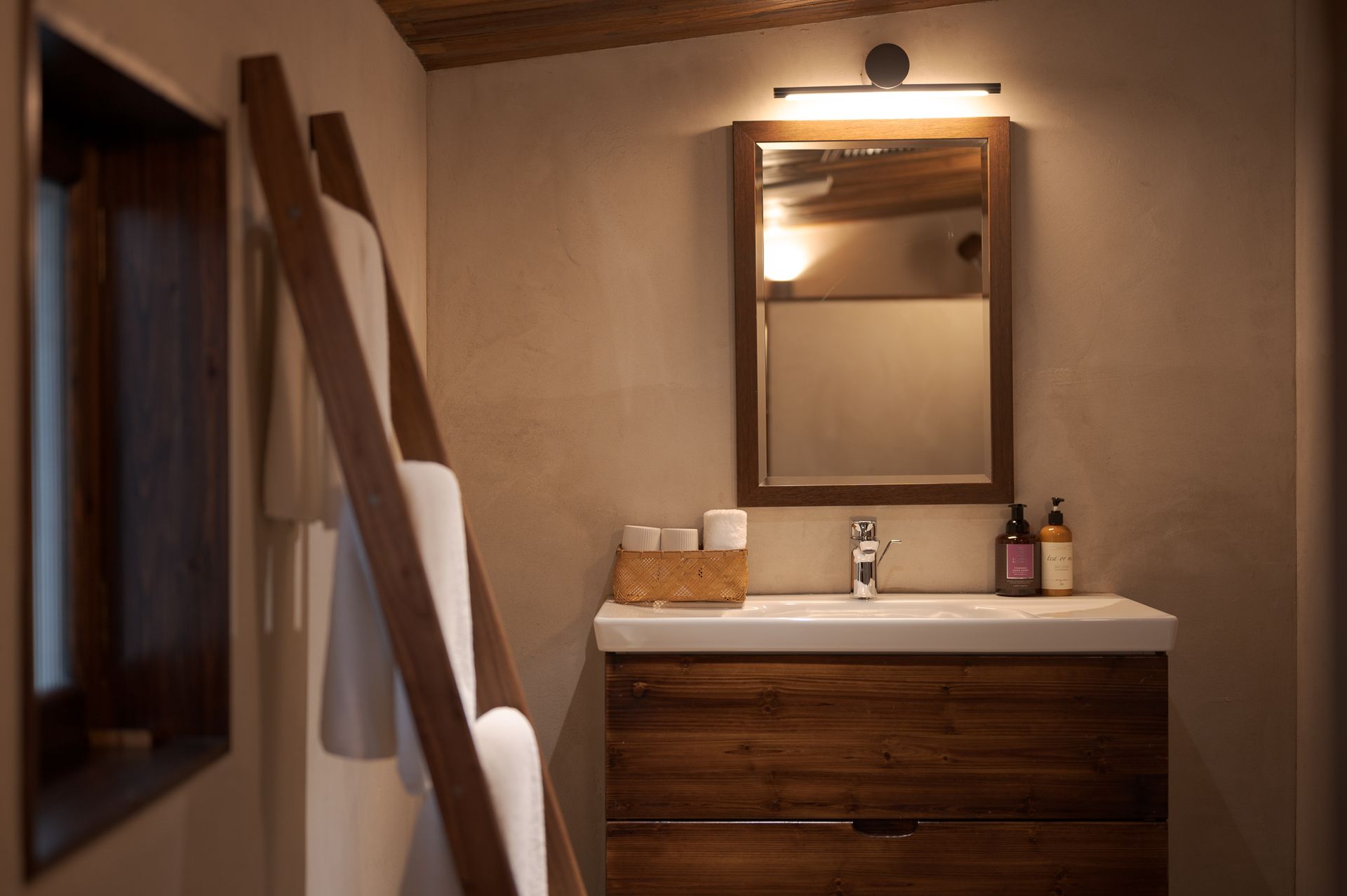 Small bathroom vanity with mirror, sink, and towels in a warm beige room.