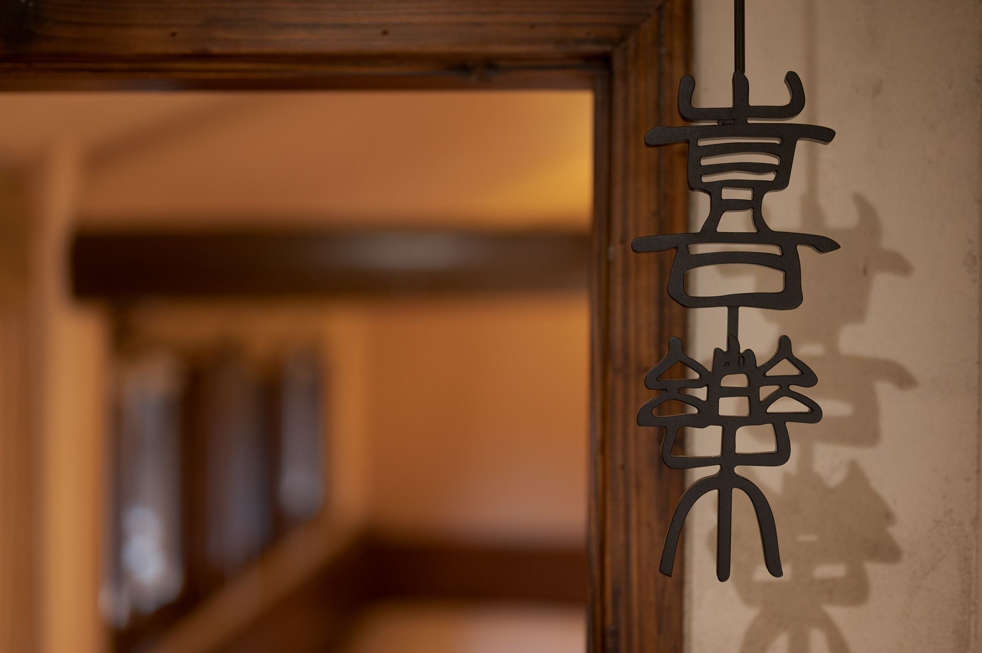 Japanese hanging sign by a wooden doorway in a softly lit interior hallway