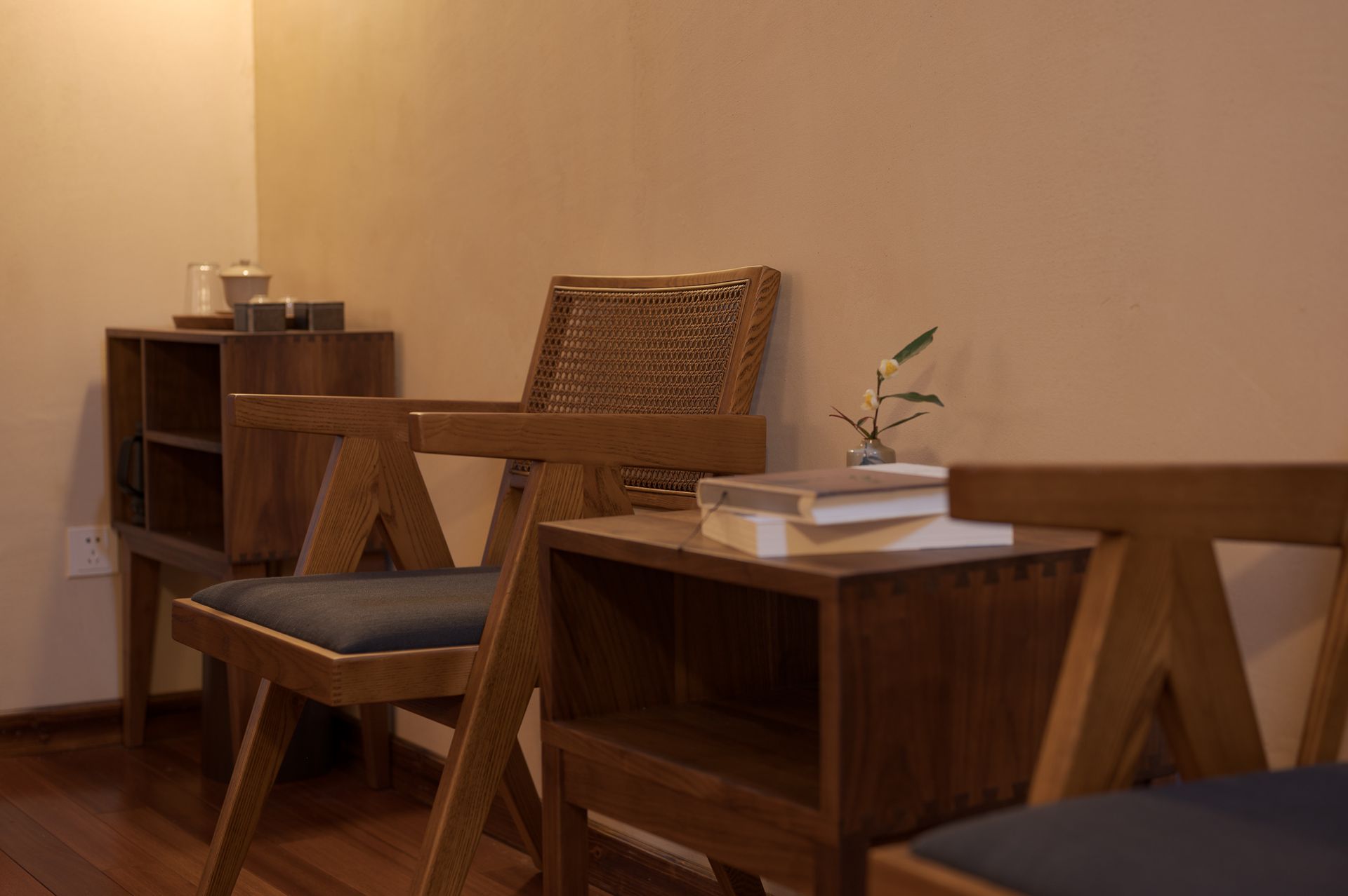 Wooden chairs and tables in a warm-toned room, with a small plant on a table and shelves along the wall.