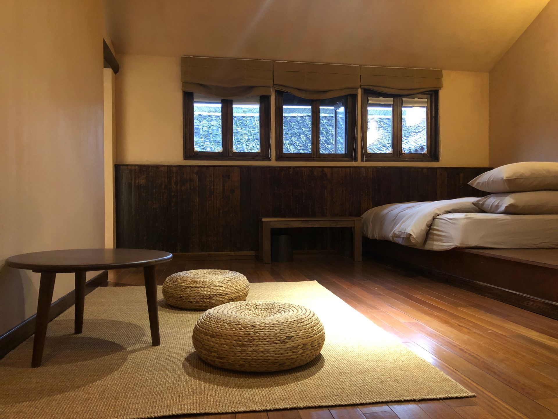 Cozy tatami room with low table, cushions, futon bed, and warm wooden interior by a window