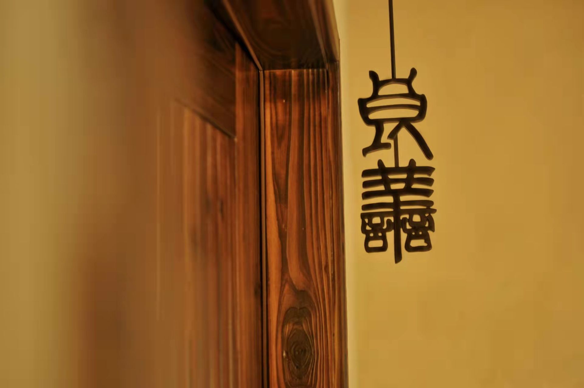 Japanese calligraphy wall hanging beside a wooden door in warm indoor lighting