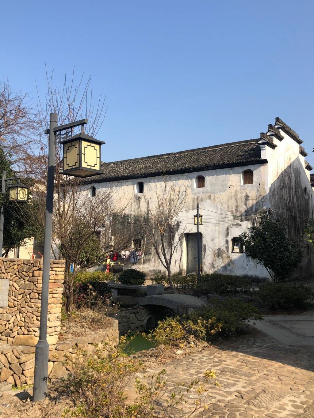 Old stone house with a tiled roof and small tower in a sunny rural courtyard