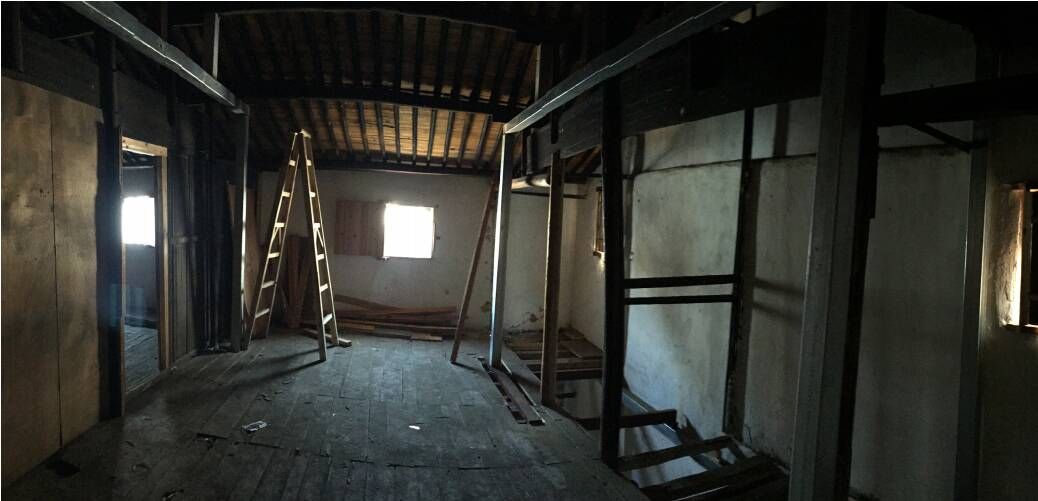Dim, narrow interior with metal framework, hanging chains, and light from a small window at the far end