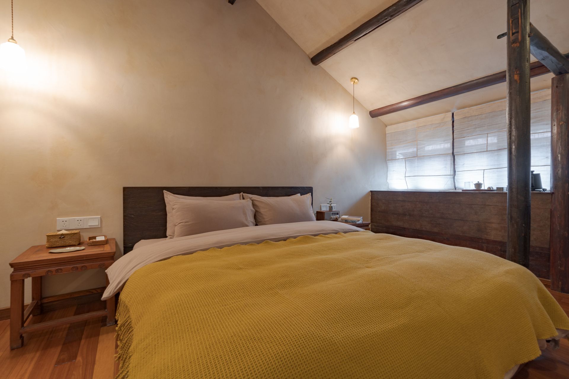 Cozy loft bedroom with a large bed, mustard blanket, and exposed wood beams