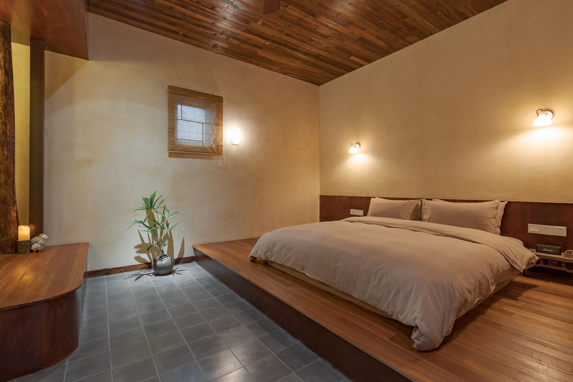 Warm minimalist bedroom with low bed, wood ceiling, tiled floor, and small indoor plant