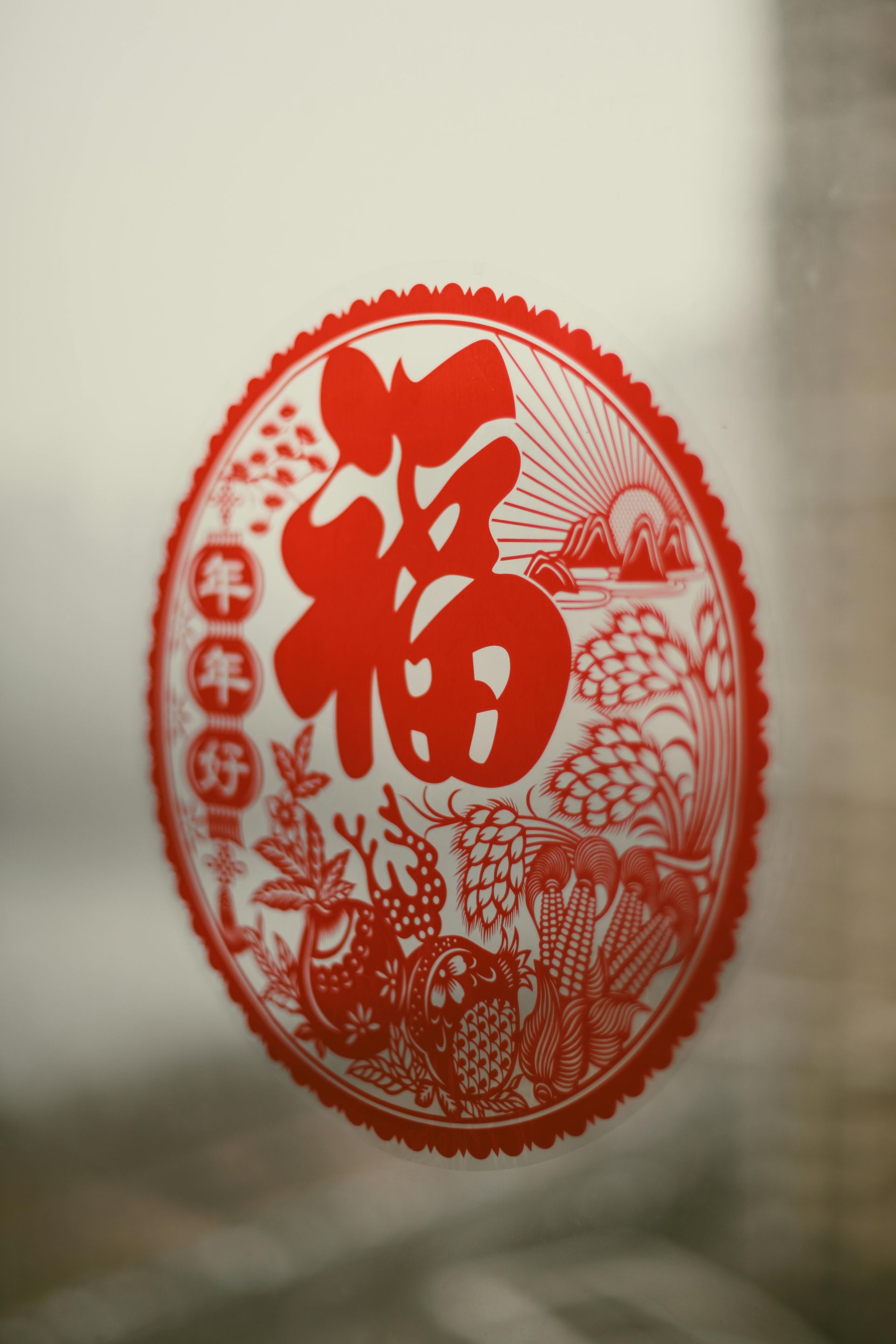 Red Chinese paper-cut “Fu” decoration on a glass window, with floral and coin motifs.