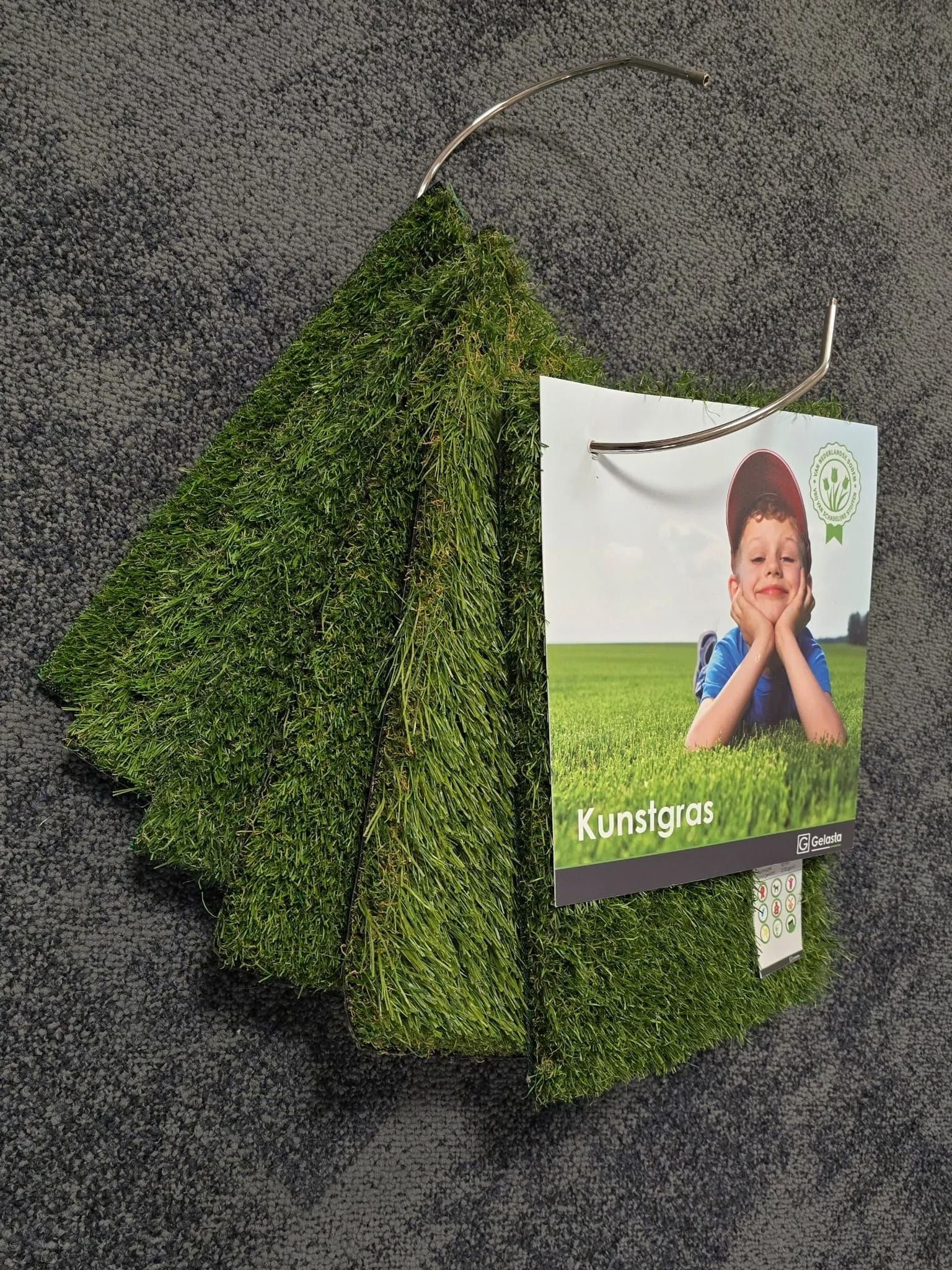Groen mosbord voor aan de muur met een foto van een lachend kind op een grijze muur.