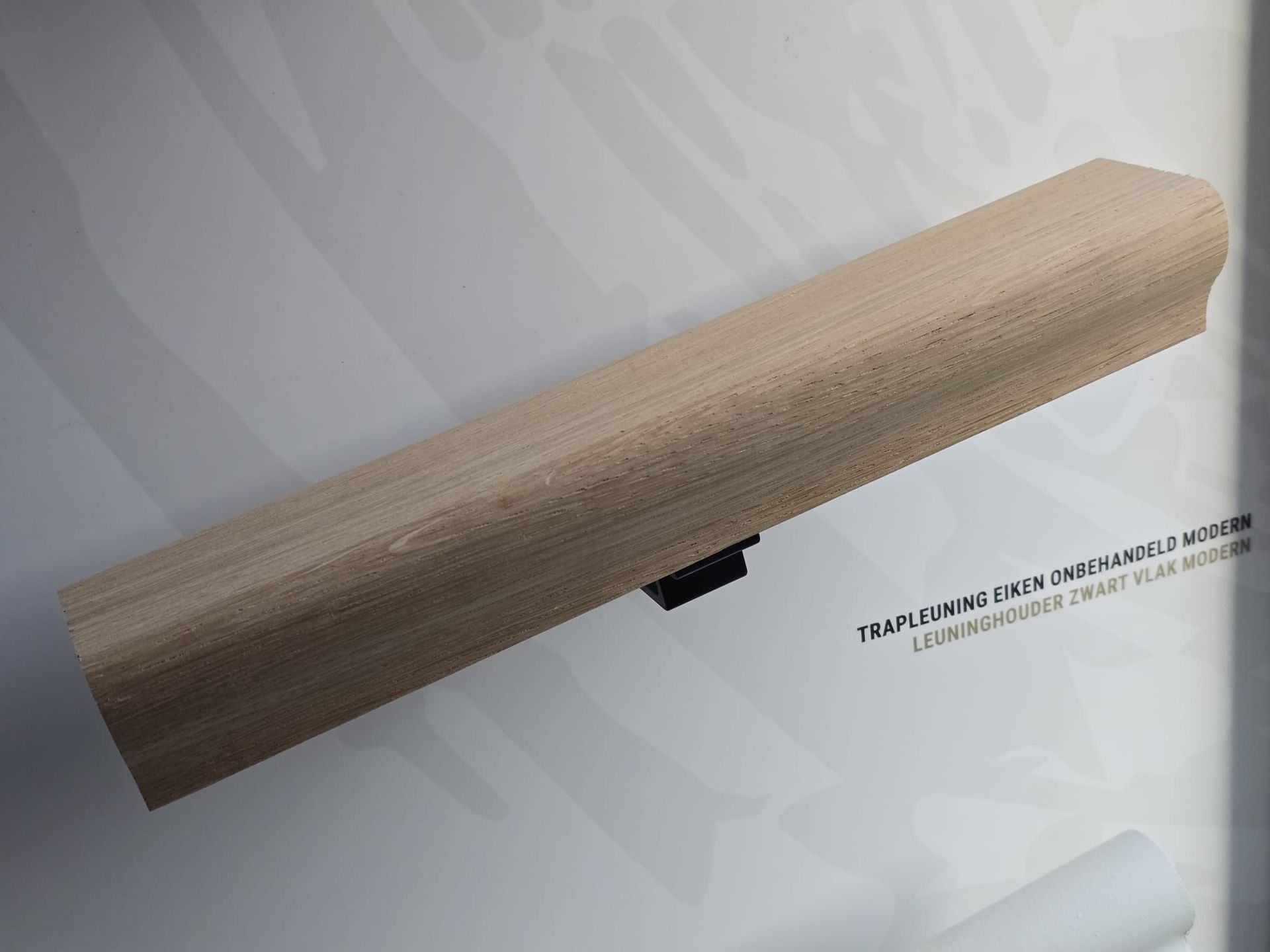 Houten wandkapstok met een zwarte beugel op een lichtgrijze achtergrond