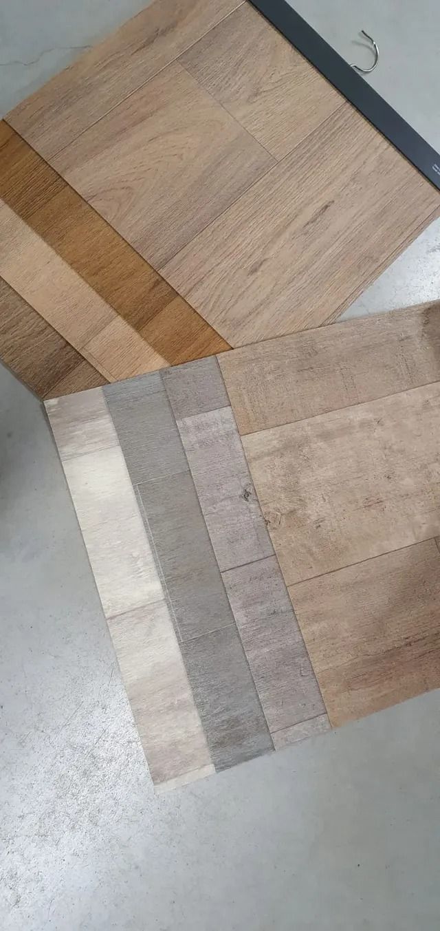 Twee vloertegels, een met houtlook en een beige tint, diagonaal geplaatst op een lichte vloer.