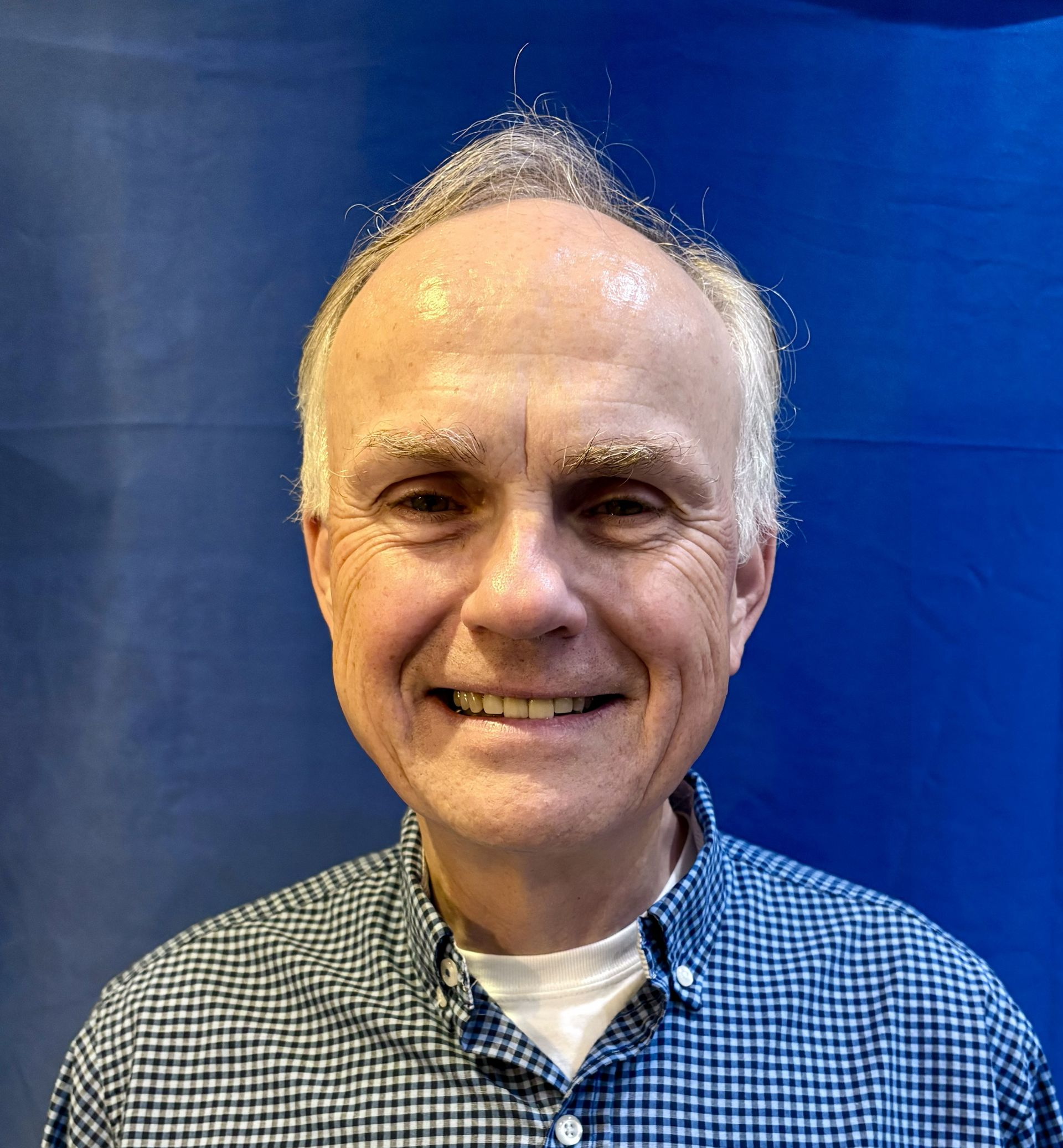 Smiling man in a blue checkered shirt against a blue background