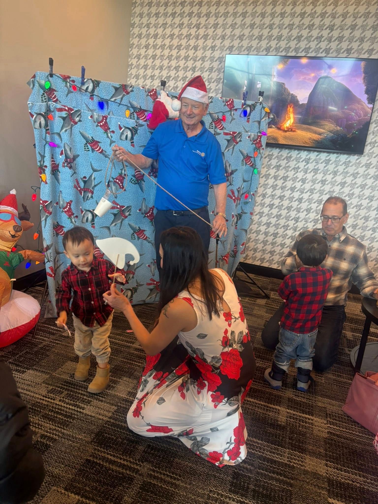 Family gathered for a holiday celebration, with a child in costume in front of a festive backdrop.