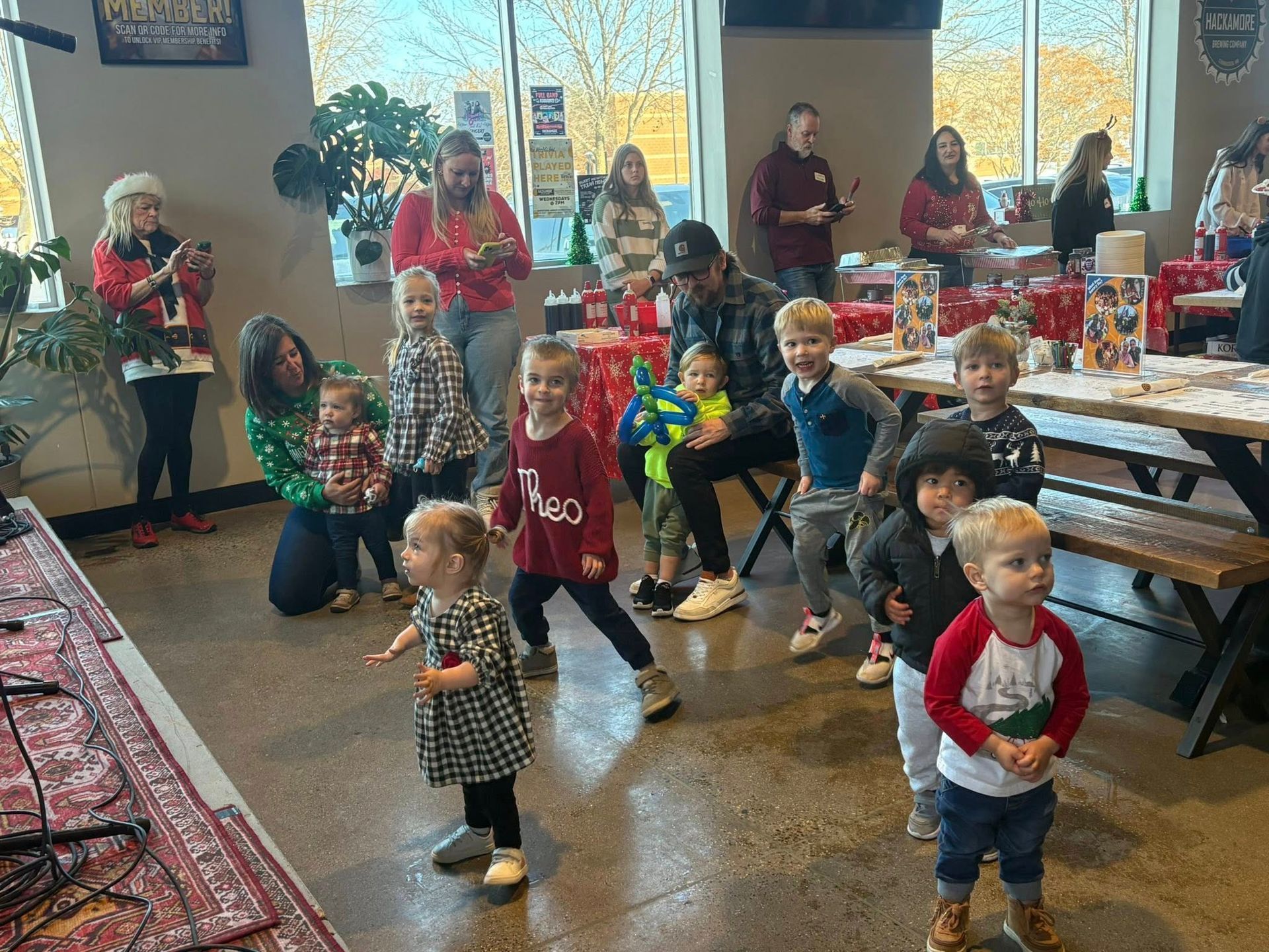 Children dancing at a holiday party in a decorated room, with gifts and festive decorations in the background