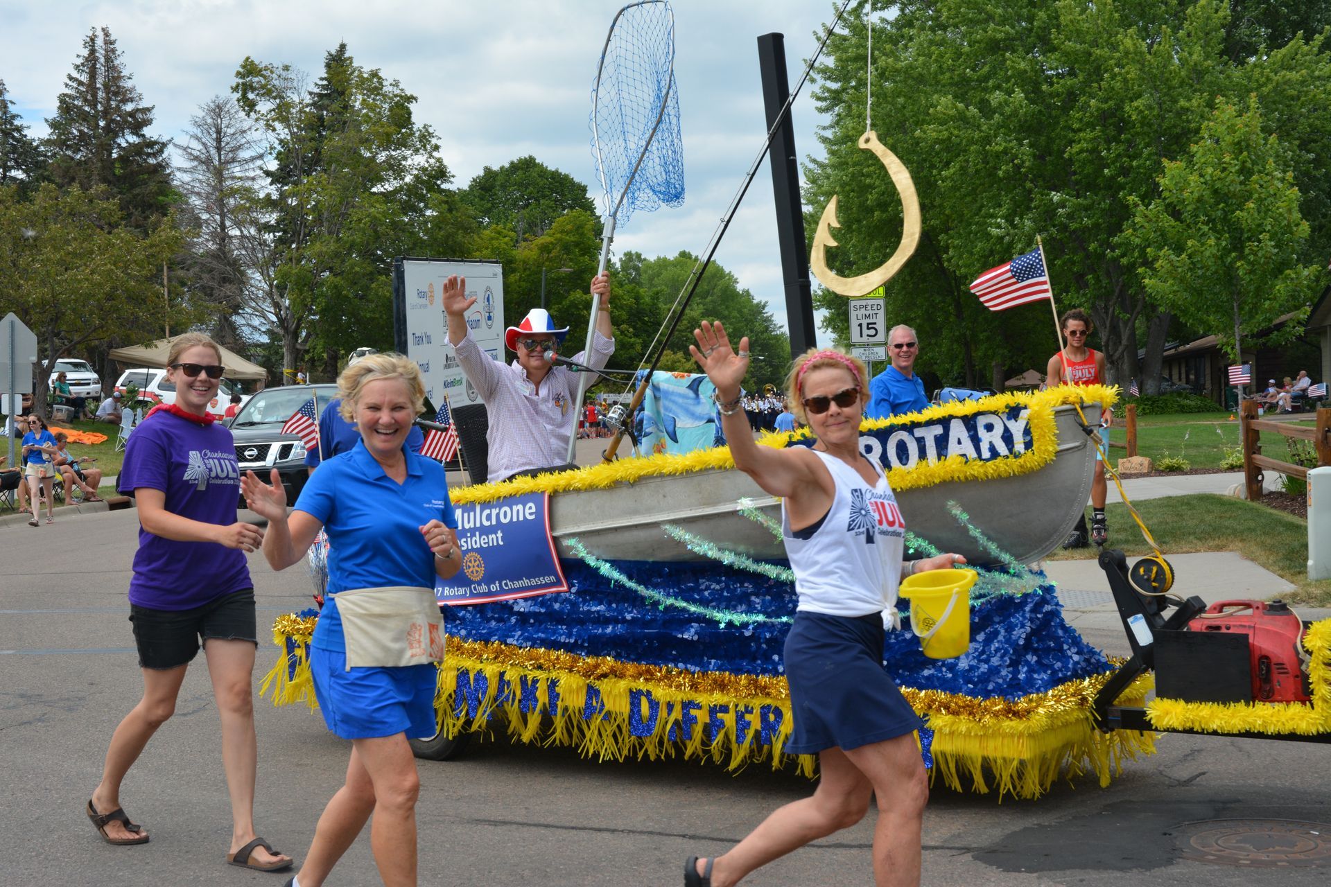 Rotary parade float with people walking beside a decorated boat-shaped display and American flag