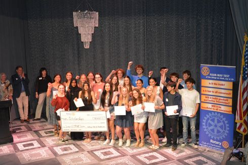 Group of people on a stage holding a large certificate, with a blue event banner on the right.