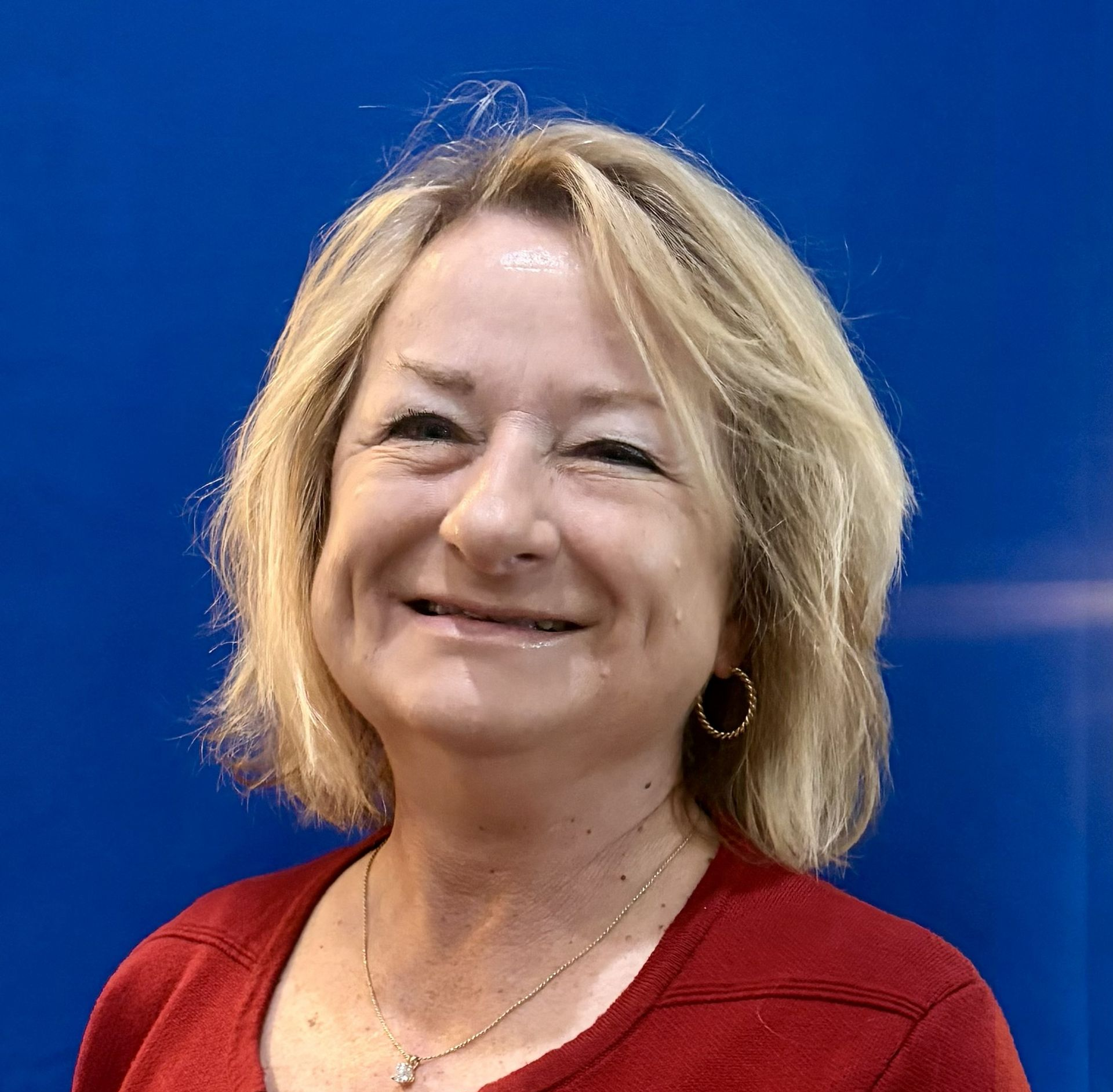 Smiling woman in a red top against a bright blue background