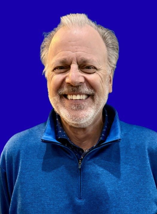Smiling man in a blue sweater against a bright blue background