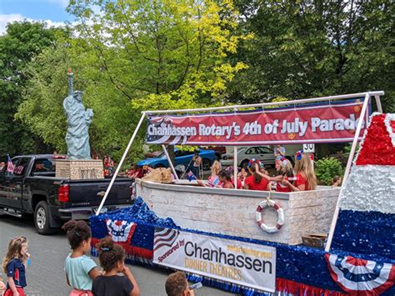Chanhassen Rotary's 4th of July parade float with red, white and blue decorations and people riding aboard