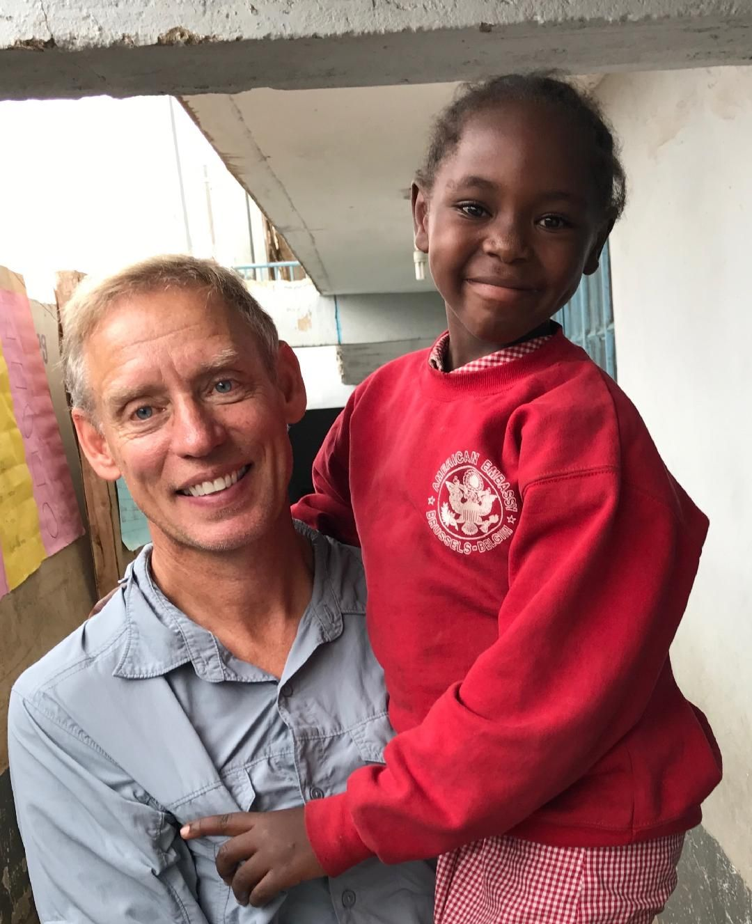 Smiling man holding a child in a red sweatshirt indoors