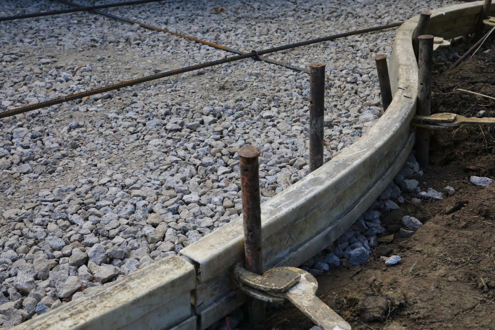 A concrete curb is being built on a gravel road. A concrete curb is being built on a gravel road.