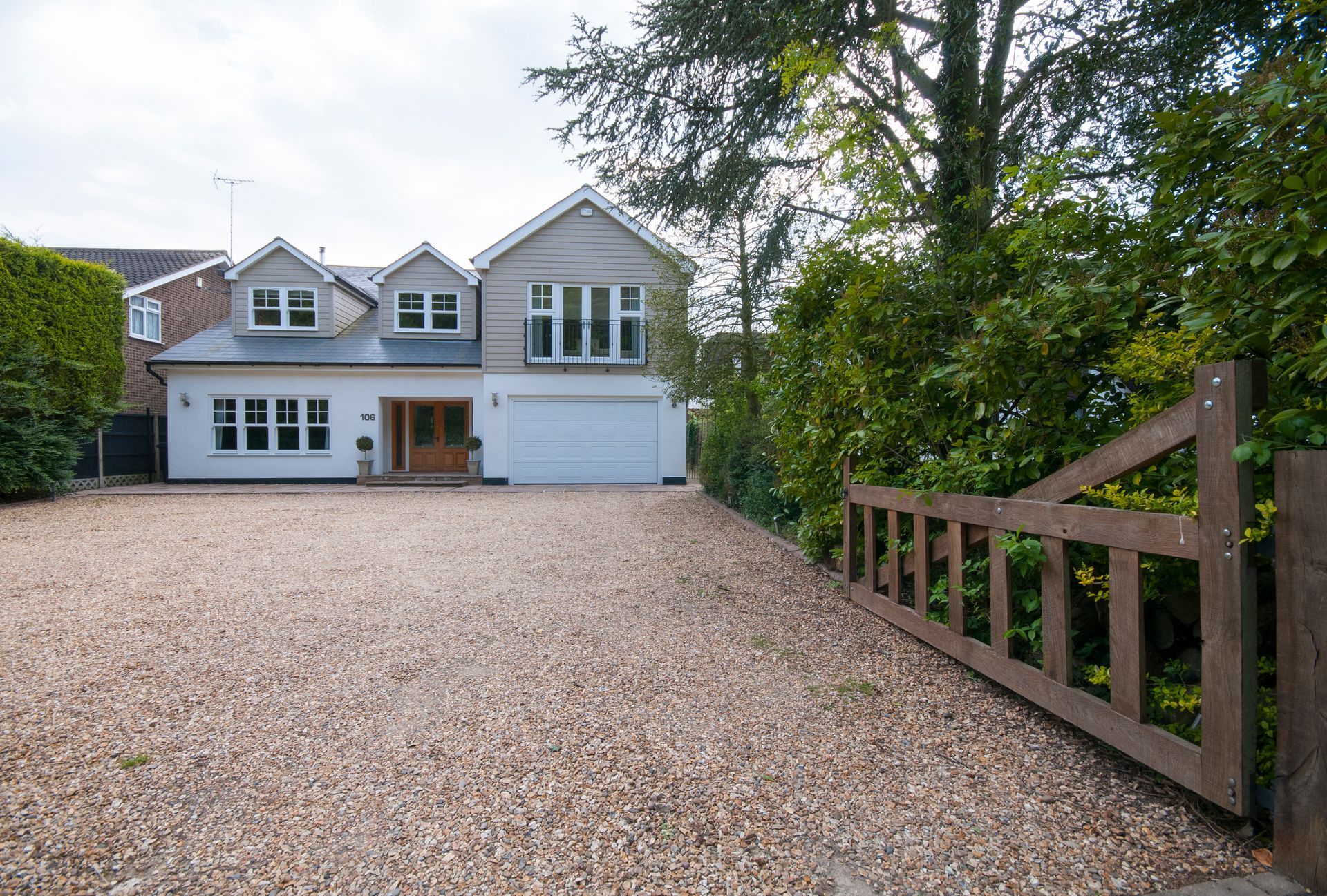 A large house with a gravel driveway and a wooden gate in front of it. A large house with a gravel driveway and a wooden gate in front of it.