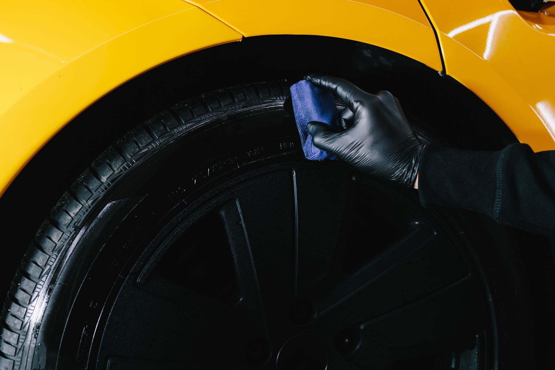 Mechanic working on a truck wheel beside an orange tool cabinet in a garage