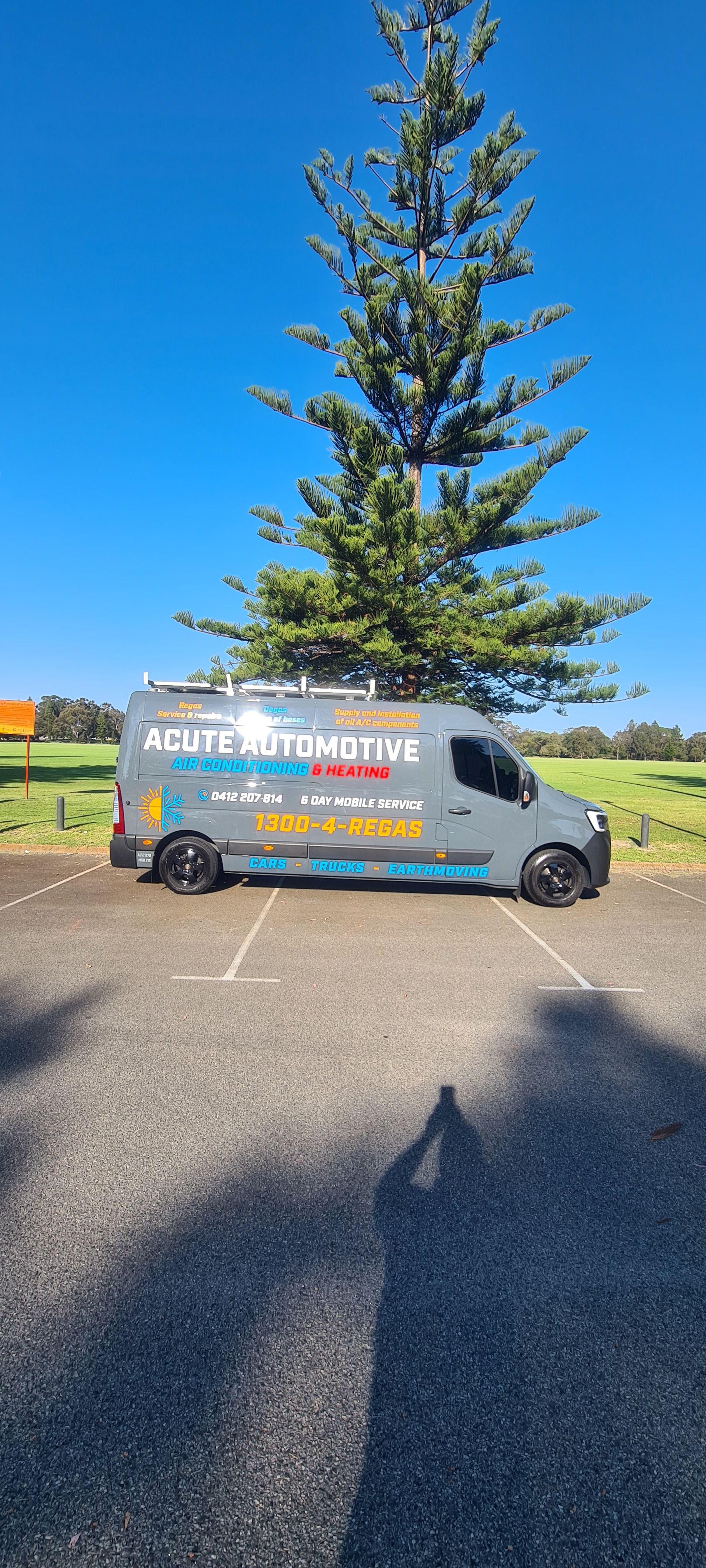 A van is parked in a parking lot next to a tree.