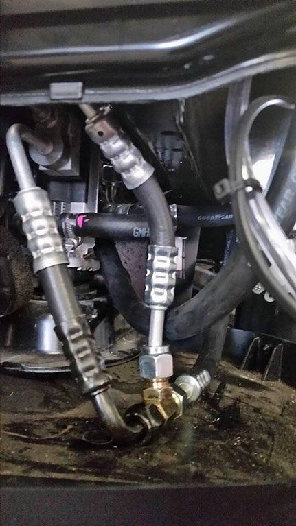 A close up of a hose attached to a car engine.