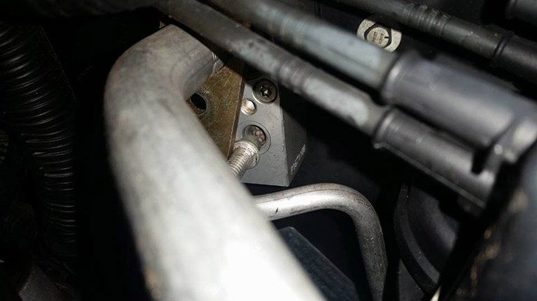 A close up of a metal pipe in a car engine.