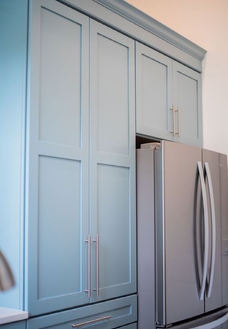 A kitchen with blue cabinets and a stainless steel refrigerator