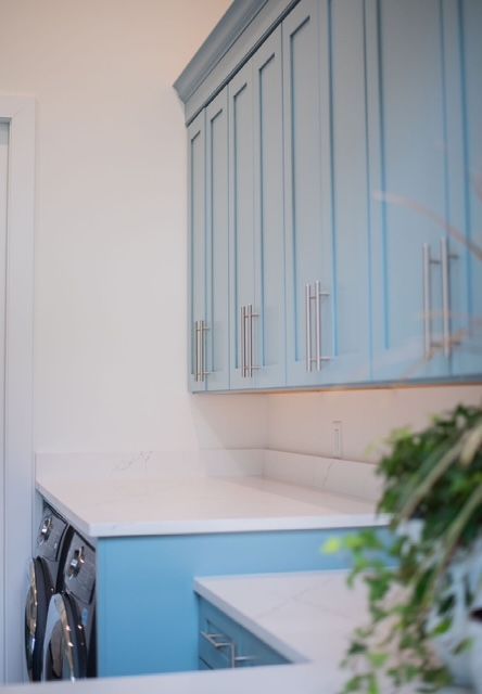 A laundry room with blue cabinets and a washer and dryer