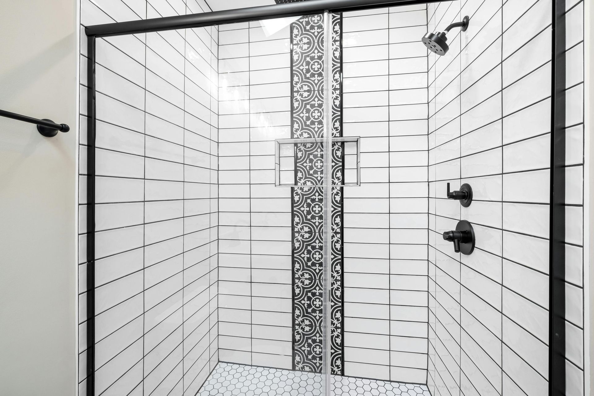 Modern tiled shower with black fixtures and a patterned center strip