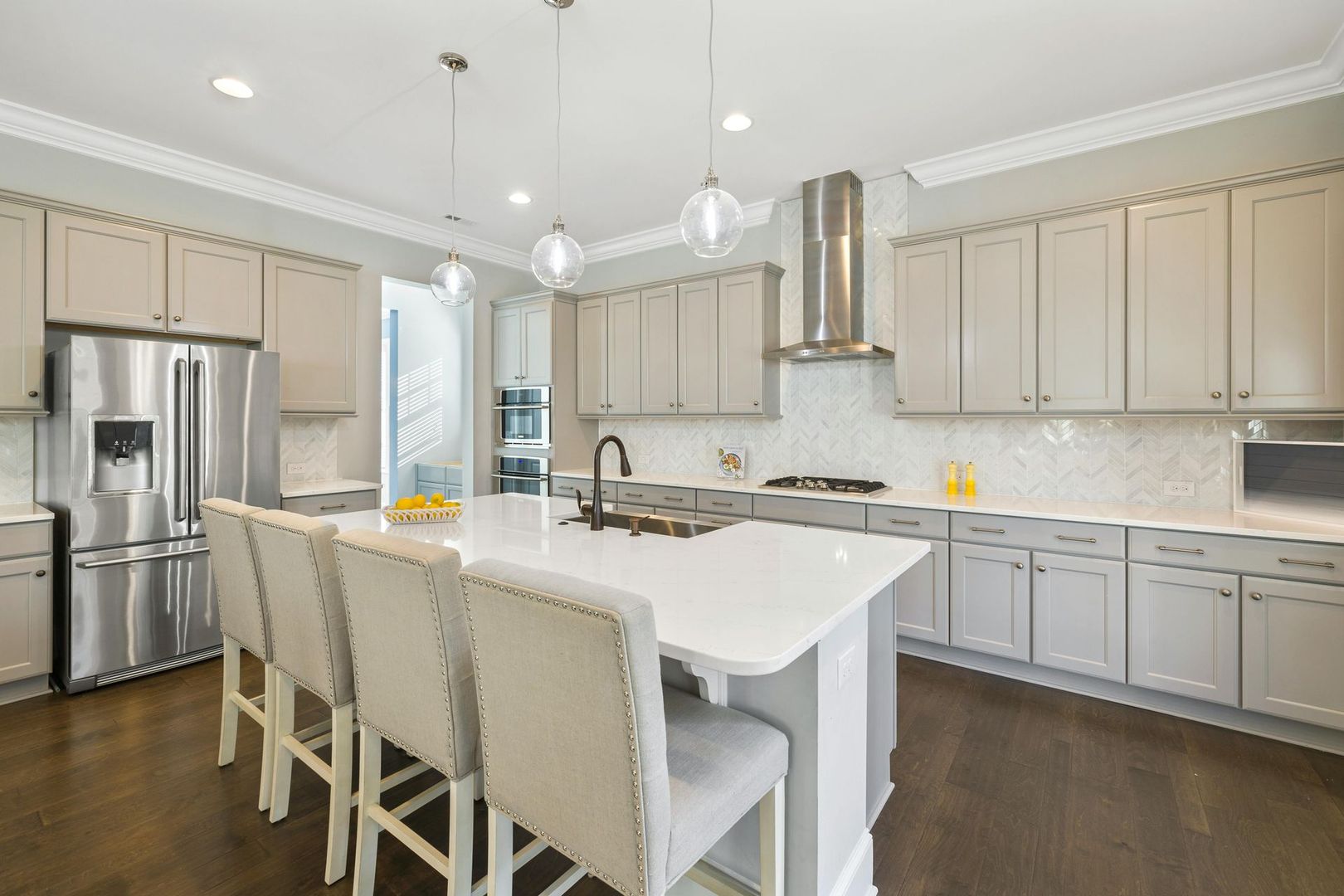 Bright modern kitchen with white island seating, stainless steel appliances, and beige cabinets