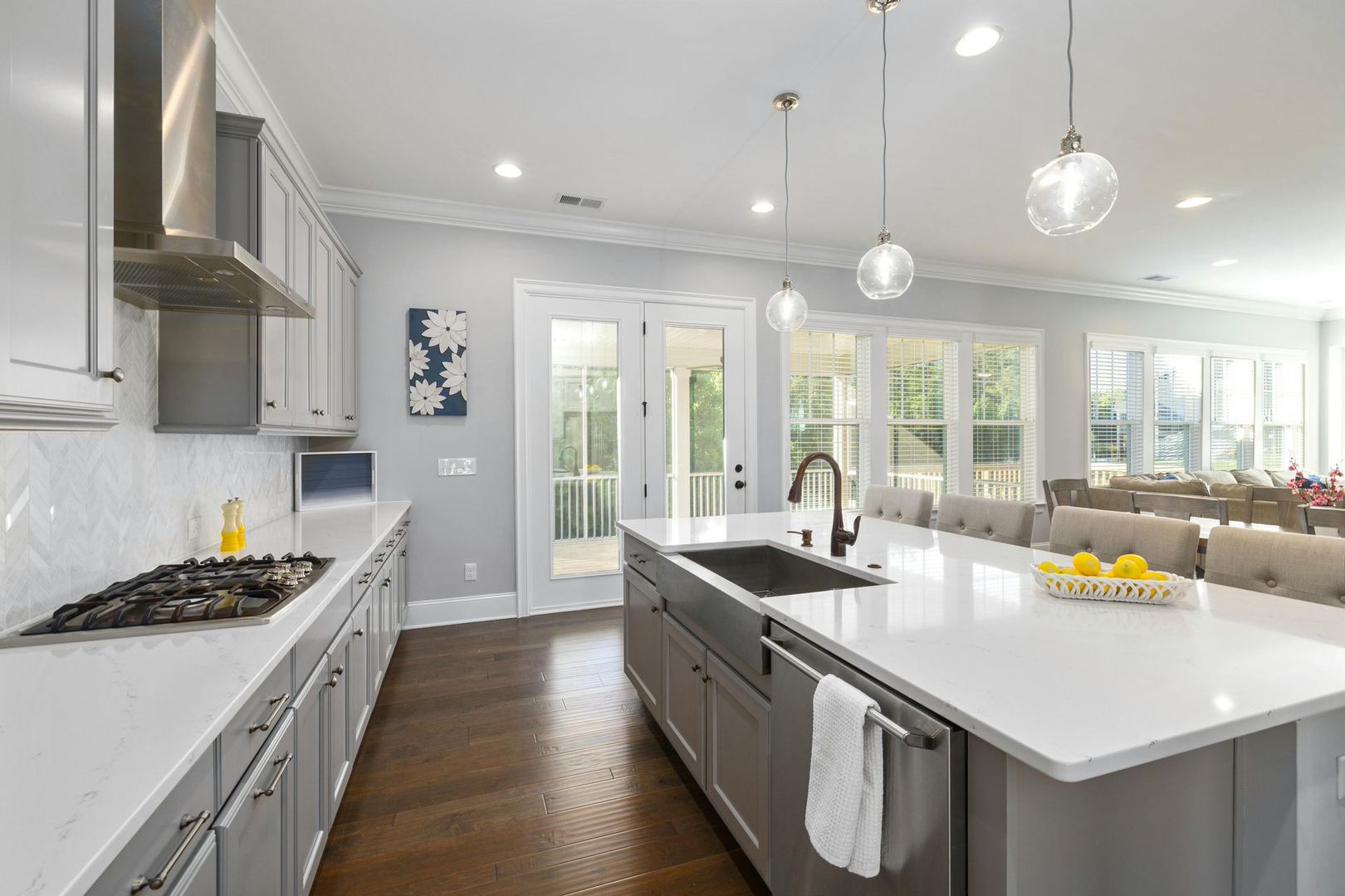 Bright modern kitchen with white counters, gray cabinets, pendant lights, and a large island