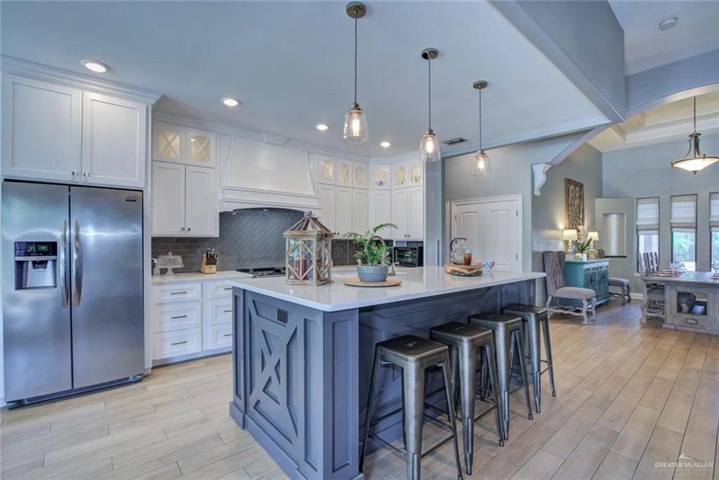 Bright white kitchen with stainless steel fridge and large dark island with bar stools