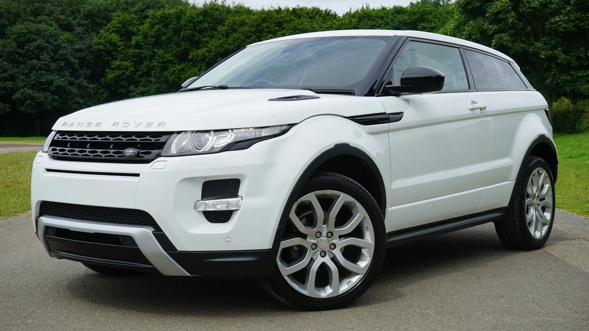 A white range rover is parked on the side of the road