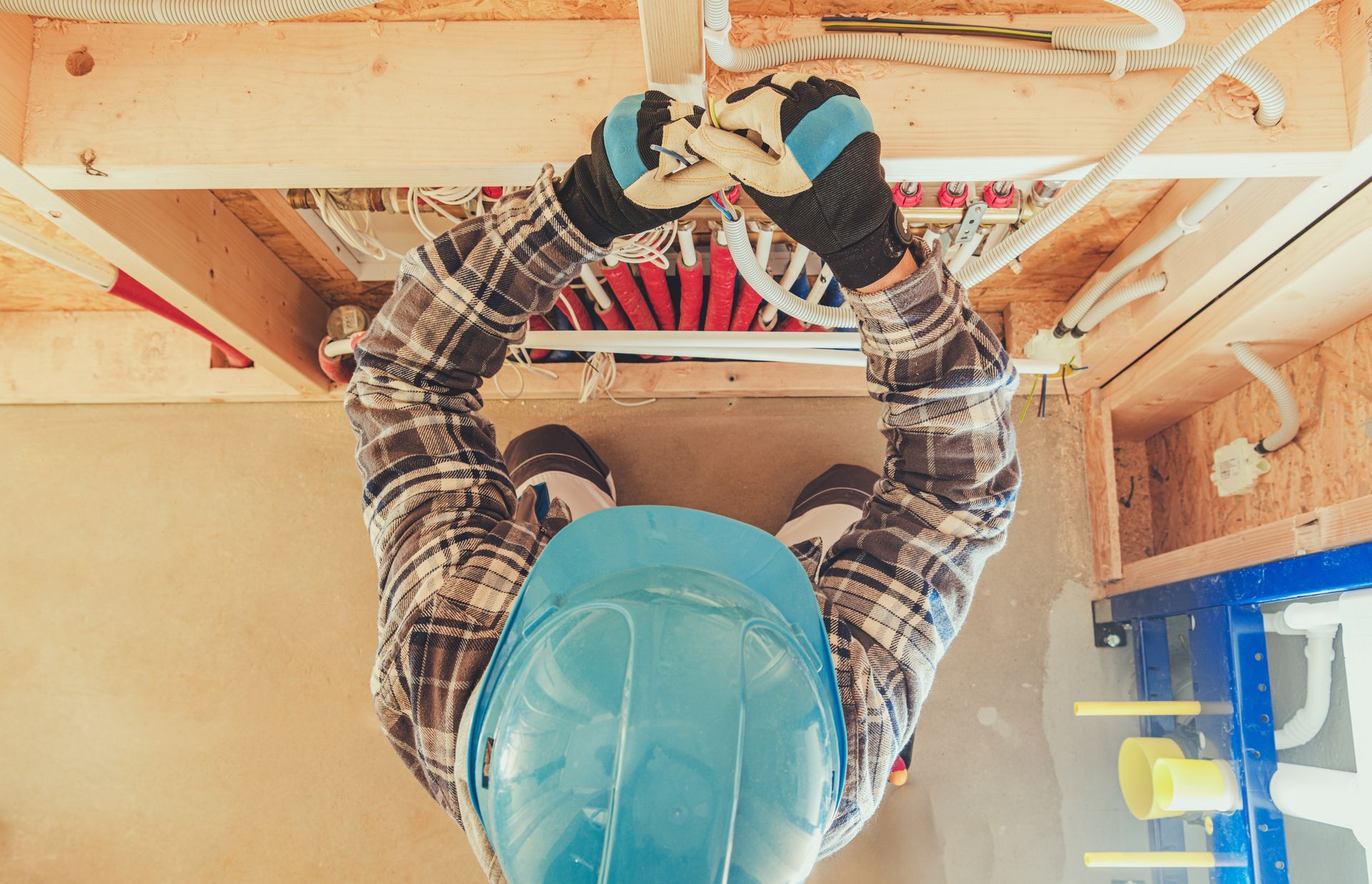 Worker in a hard hat organizing electrical wires inside a wall opening. Worker in a hard hat organizing electrical wires inside a wall opening.
