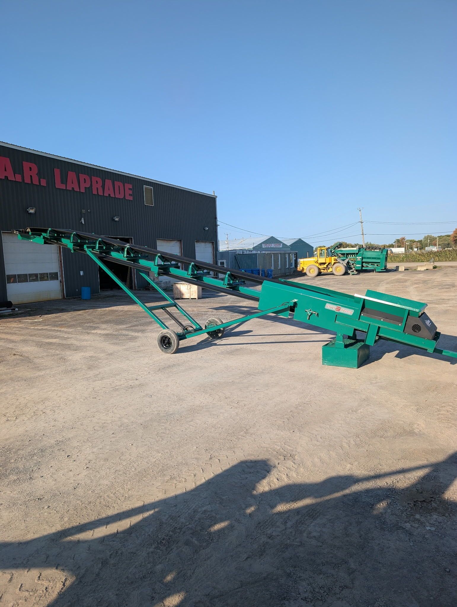 Green industrial conveyor belt extending from a building with 
