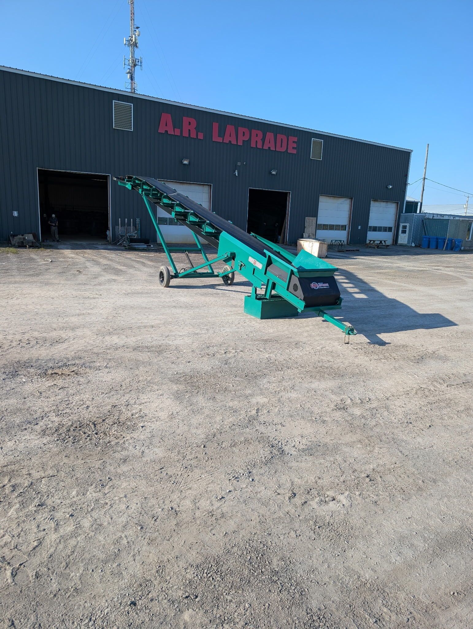 Green conveyor belt outside a building labeled 