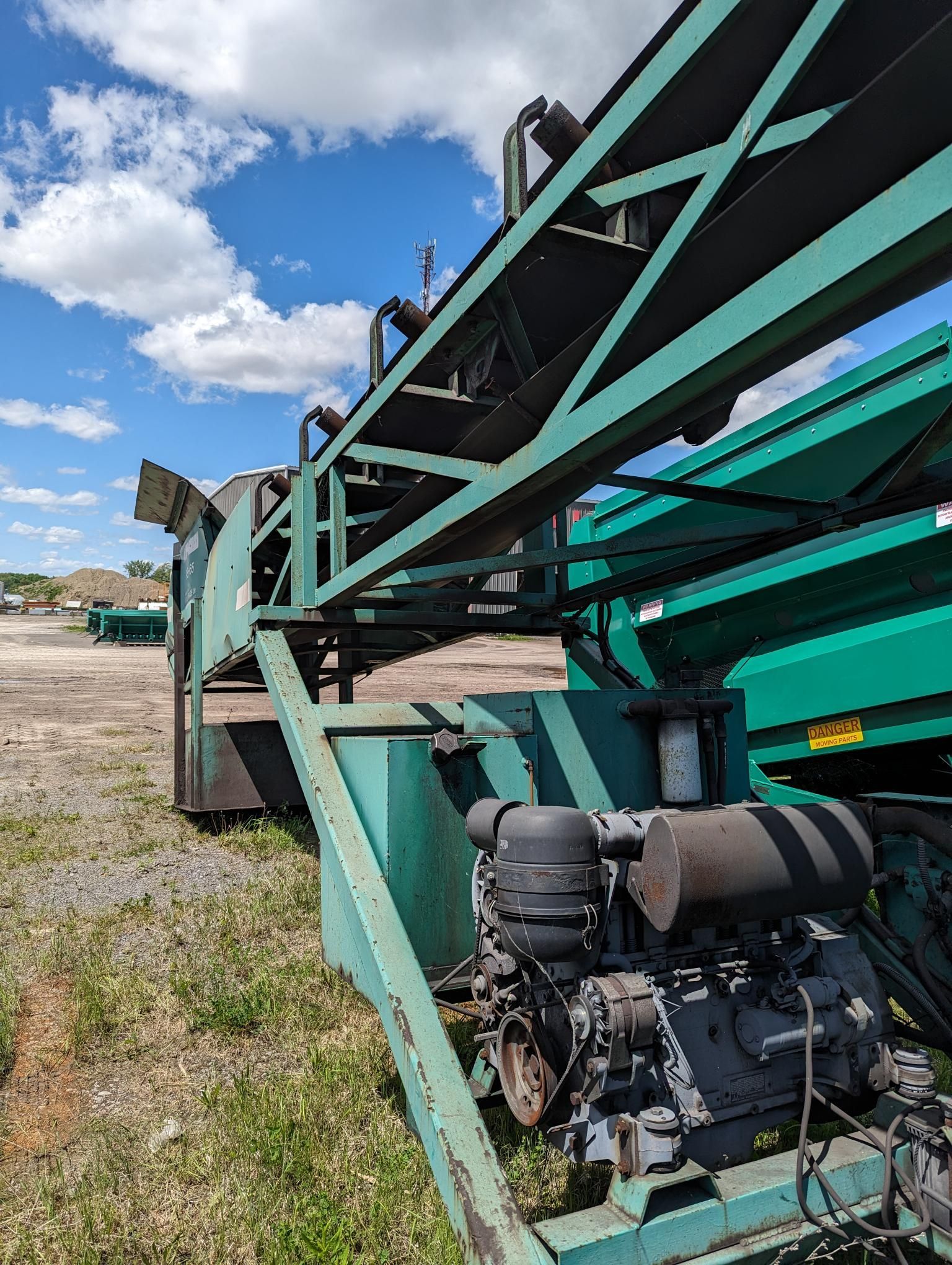 A green machine is sitting on top of a trailer in a field.