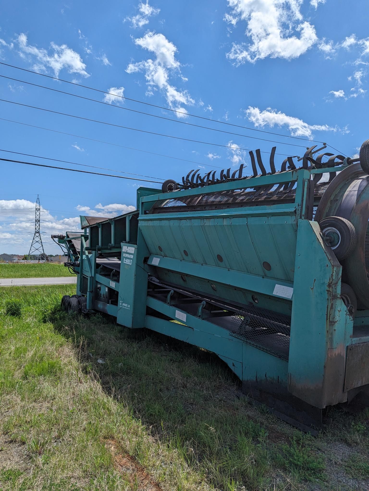 A green machine is sitting in the middle of a grassy field.