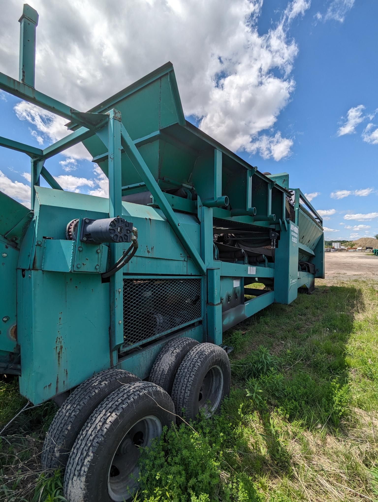 A green machine is sitting in the middle of a grassy field.