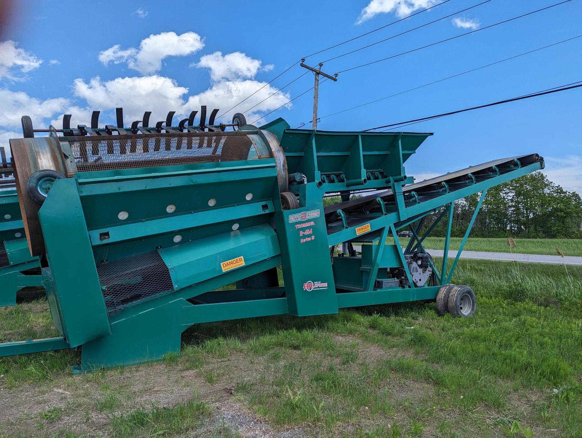 A green machine is sitting in the middle of a grassy field.
