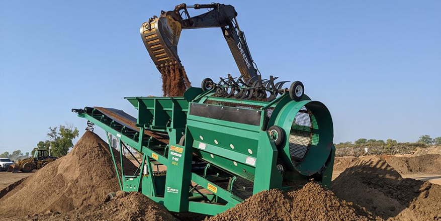 Une machine verte est posée au sommet d'un tas de terre.