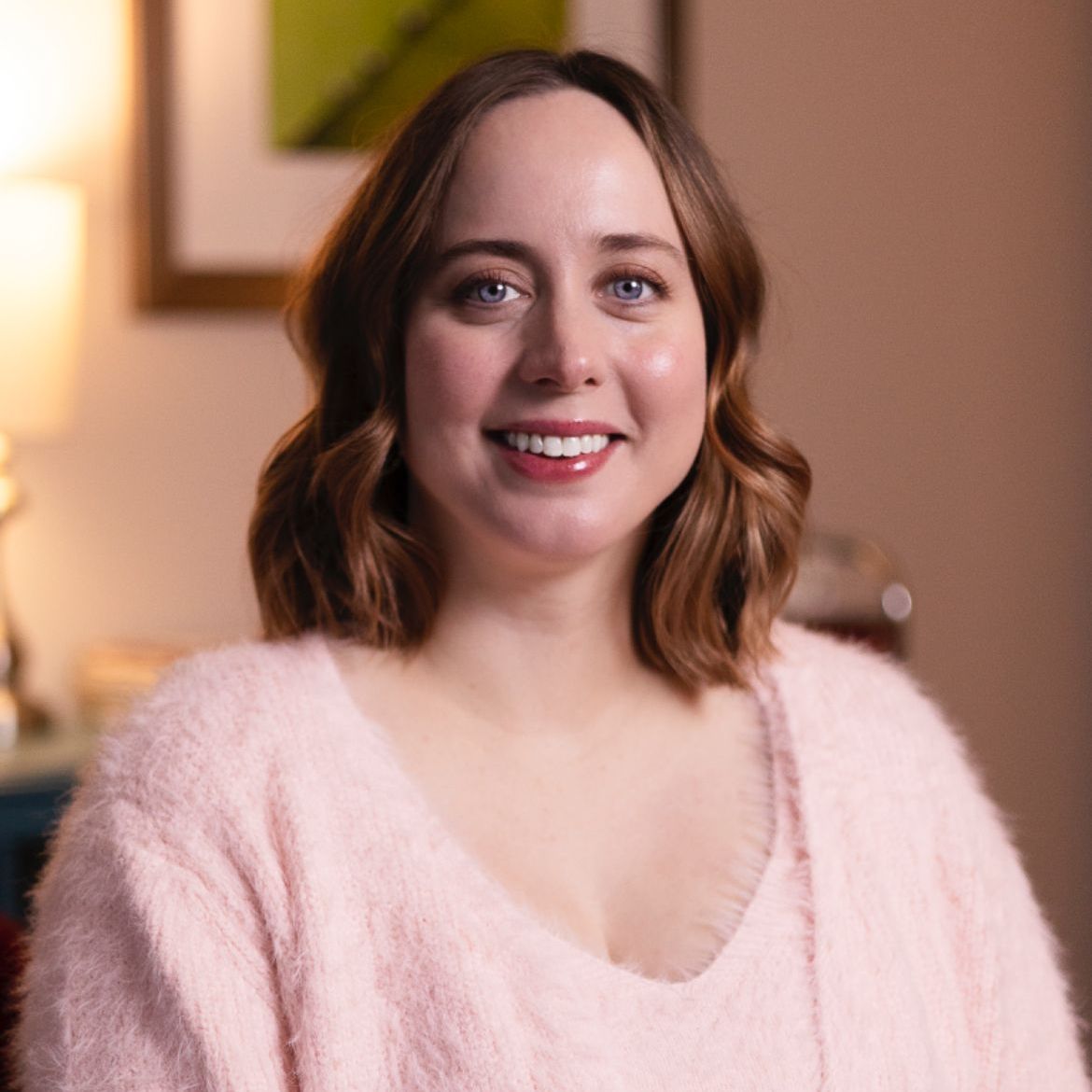 A woman in a pink sweater is smiling for the camera.