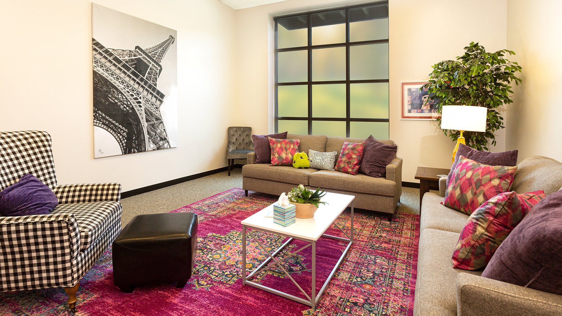 A living room with a couch , chair , coffee table and rug.
