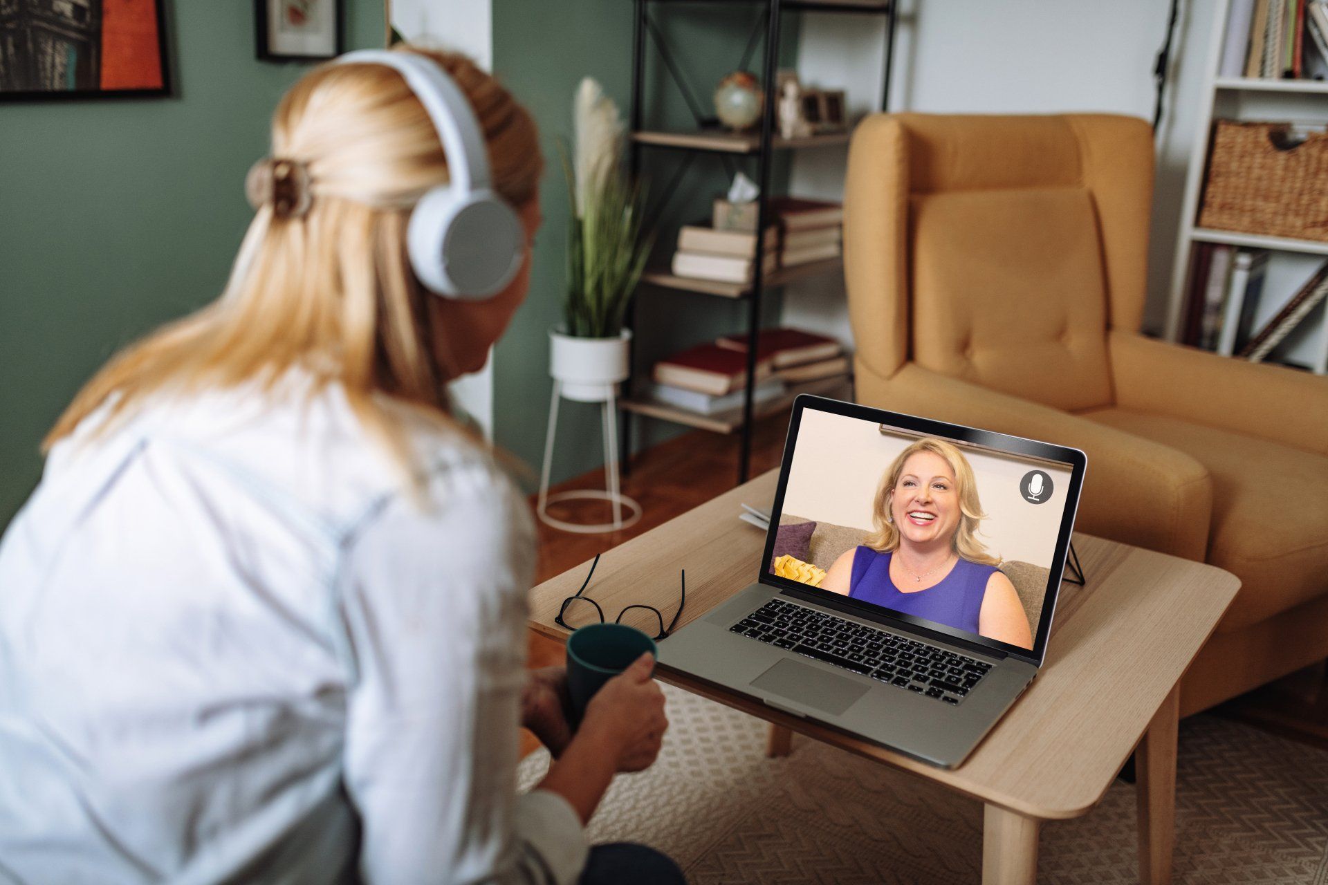A woman wearing headphones is sitting in front of a laptop computer.